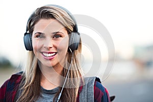 Jamming away in the city. Portrait of an attractive young woman wearing headphones while walking through the city.