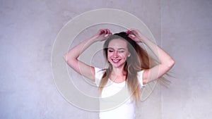 Portrait of attractive young woman who relaxing, dancing at home in room on background of light day wall background.