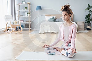 Portrait of attractive young woman working out at home, doing yoga exercise on white mat