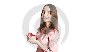 Portrait of a Ñaucasian happy toothy smiling girl in dress holding present box and looking at the camera. Brunette young women
