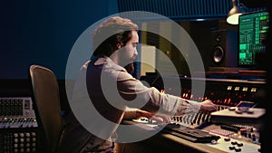 Portrait of audio technician adjusting volume levels on recordings