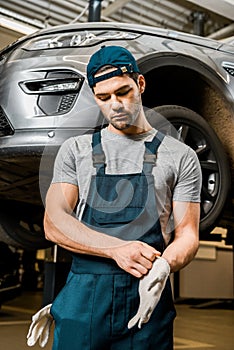 portrait of auto mechanic in uniform wearing protective gloves