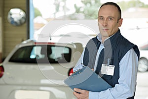 portrait automobile mechanic with clipboard in car repair store