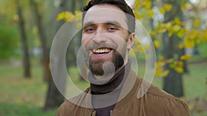Portrait in autumn park outdoors happy smiling positive smile Caucasian bearded man guy male husband father boyfriend