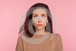 Portrait of awkward funny young woman with brunette hair making silly comical face with eyes crossed, thinking intensely