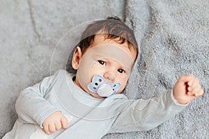 Portrait of baby boy angry, furious, frowning and agressive lying on a bed. Childrens emotions