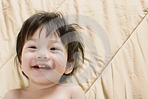 Portrait Baby Boy Asia Smile on Bed with space for text.