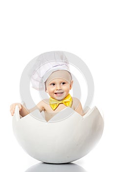 Portrait baby boy dressed in s chef`s hat sitting in egg shell. isolated on white background. Children`s Emotions