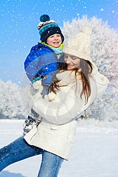 Portrait of baby boy and mother in winter day - snow is falling