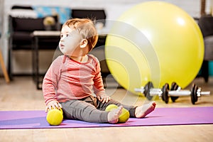 Baby boy portrait with dumbbells and fitness ball at home