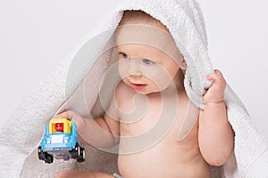 Caucasian, cheerful child after bath playing with a toy. White background.