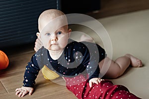 Portrait of a baby crawling on the floor and looking into the camera.