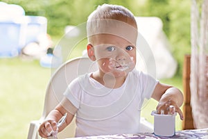 Portrait of a baby eating with a stained face.