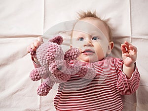 Portrait of a baby girl, 8 months old, playing with a soft toy, top view, close-up. A mischievous, beautiful girl with fair skin