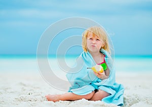 Portrait of baby girl eating pear on beach