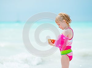 Portrait of baby girl holding shell on beach