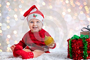 Portrait of a baby girl with a Santa hat holding a Christmas ornament