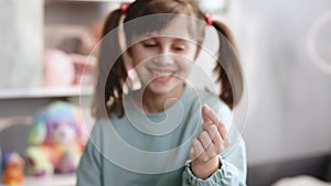 Portrait of a baby girl with a toothless smile. Shows a ripped tooth into the camera in an extended hand. Shift focus