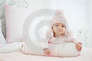 Portrait of a baby in a hat on the bed in his room