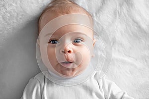 Portrait, baby, little cheerful boy on a white blanket, close-up.