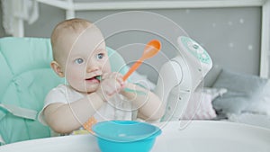 Portrait of baby sitting on highchair with spoon