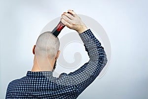 Portrait of back bald man head holding a trimmer in his hand. The concept of hair loss and hair transplantation