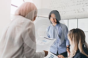 Portrait from back of short-haired blonde female manager analysing reports and graphs. Indoor photo of international