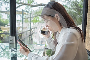 Portrait background young business woman drinking coffee and using mobile phone in restaurant with glass are backdrop