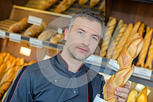 Portrait baker holding baguette