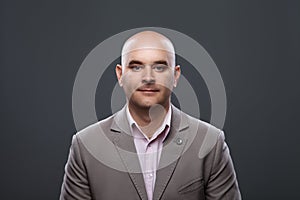 Portrait of a bald affable man in a suit against a dark background