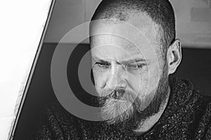 Portrait Of A Bald Bearded Man With Beautiful Blue Eyes With A Focused Look. Black And White Photo