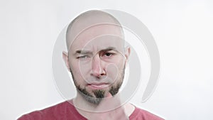 Portrait of a bald bearded man holding his nose against a bad smell. White background.