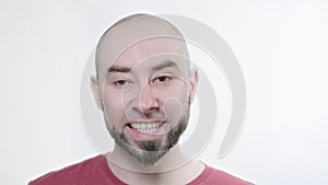 Portrait of a bald, bearded, yawning man in close-up on a white background. Fatigue and drowsiness