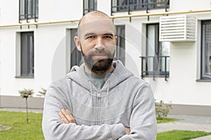 Portrait of a bald man 30-35 years old against the background of new beautiful multi-storey buildings, looking into the camera.