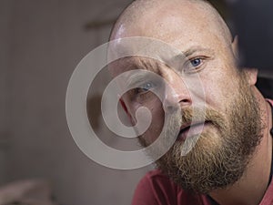 Portrait of a bald man with a beard with beautiful blue eyes, looking away from the camera. man makes selfie