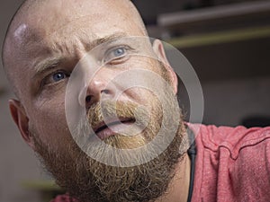 Portrait of a bald man with a beard with beautiful blue eyes, looking away from the camera. man makes selfie