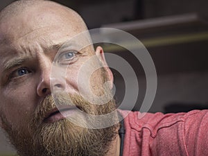 Portrait of a bald man with a beard with beautiful blue eyes, looking away from the camera. man makes selfie