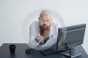 Portrait of a bald man at a desk looking at a report and cursing. The displeased chief reports to the subordinate.