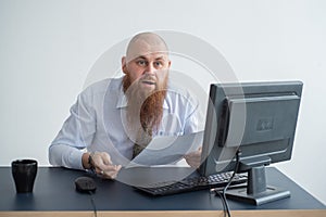 Portrait of a bald man at a desk looking at a report and cursing. The dissatisfied boss dismisses the subordinate.