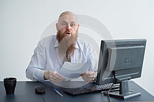 Portrait of a bald man at a desk looking at a report and cursing. The dissatisfied boss dismisses the subordinate.