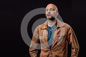 Portrait of a bald man in his 40s dressed in brown suede jacket.