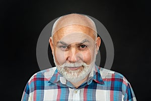 Portrait of an bald old mature senior man with grey beard on black studio background. Older grandfather, grandpa