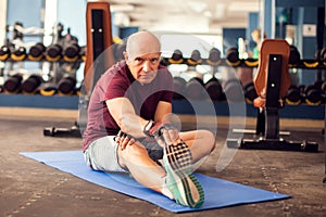 A portrait of senior man doing stretching after training in the gym. People, healthcare and lifestyle concept