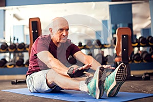 A portrait of senior man doing stretching after training in the gym. People, healthcare and lifestyle concept