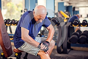 A portrait of senior man feeling strong knee pain during training in the gym. People, healthcare and lifestyle concept