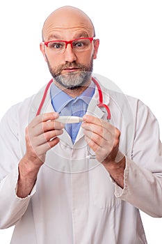 Portrait of bald slim doctor wearing white uniform, blue shirt, red stethoscope and glasses on white background. Caucasian in 40s