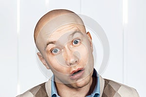 Portrait of a bald stupid surprised guy with open mouth