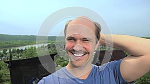 Portrait, balding young man in the countryside looking at the camera, smiling