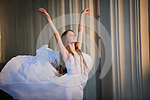 Portrait of a ballerina girl with loose long hair in a white skirt flowing