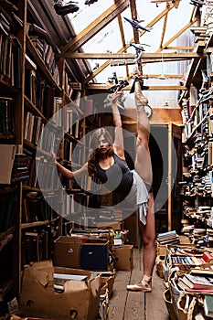 Portrait of ballerina girl in vintage book store wearing casual clothes